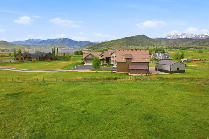 Expansive green acreage featuring a primary residence with an attached garage, a separate barn-style structure, and a large metal outbuilding