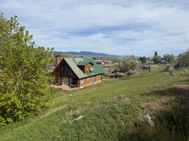 Log-sided residence featuring a steep green metal roof and a prominent stone chimney