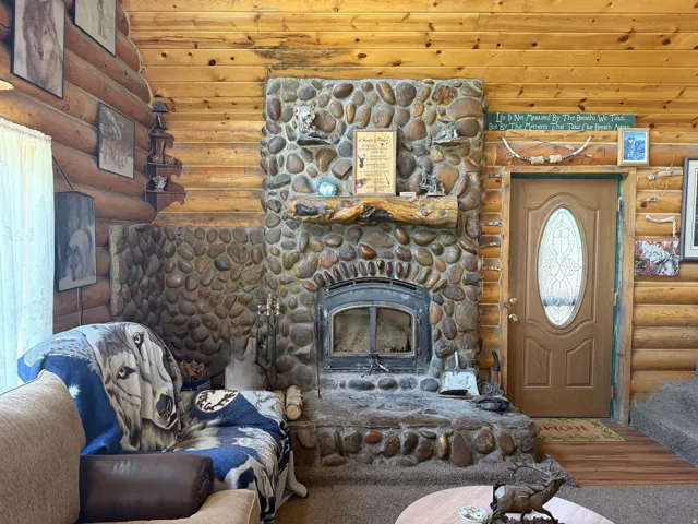 River rock fireplace with a wood-burning insert and log mantel