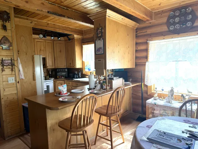 Expansive kitchen featuring wood-finish cabinetry, a breakfast bar, track lighting, and a window with natural light