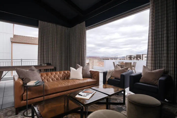 Expansive indoor-outdoor living area featuring large sliding glass doors, a dark coffered ceiling, and patterned floor-to-ceiling drapery