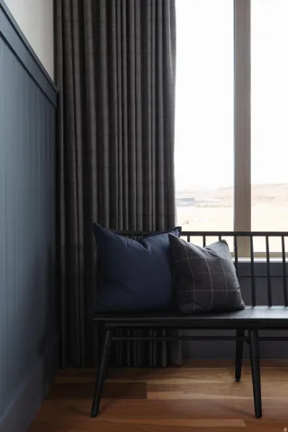 Floor-to-ceiling window with textured drapes, wood-finish flooring, and paneled wall detailing