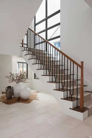Grand staircase featuring wood-finish handrails, black metal balusters, and carpeted treads