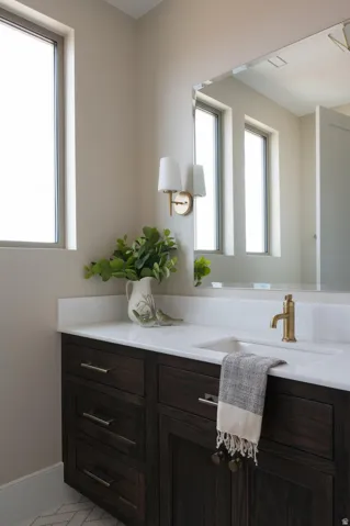 Bathroom vanity featuring dark wood-finish cabinetry with silver-tone hardware, a white countertop, and an undermount sink