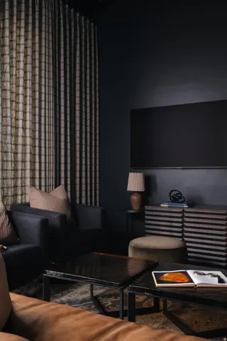 Living area with dark walls and full-height patterned drapery