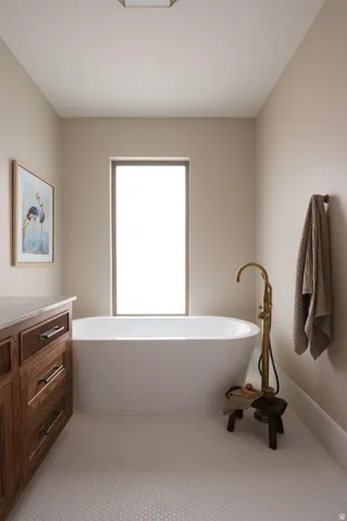 Freestanding soaking tub with a floor-mounted brass faucet, set against a window