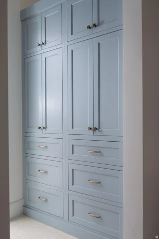Full-height built-in cabinetry featuring a soft blue finish, recessed panel doors, and brass hardware