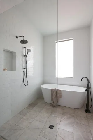 Spacious bathroom featuring a freestanding soaking tub with a floor-mounted matte black faucet