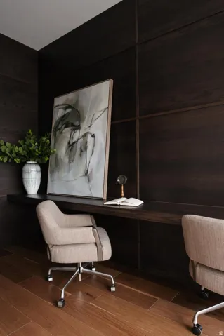 Dedicated workspace featuring rich wood-finish wall paneling, a full-width built-in desk, and warm wood-finish flooring