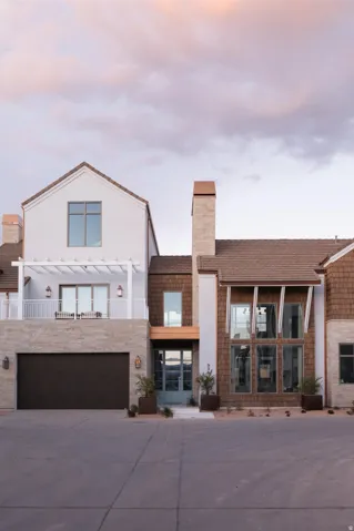 Contemporary facade featuring mixed materials including white stucco, natural wood shingle siding, and stacked stone accents