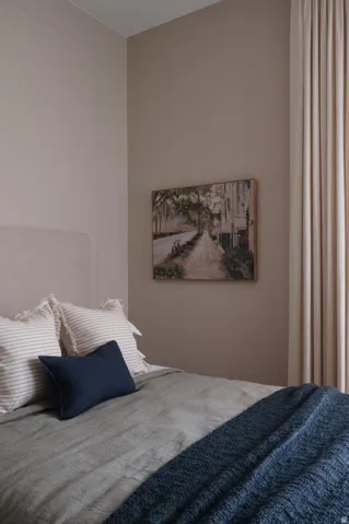 Warm-toned walls accenting a textile headboard, with full-height drapery panels providing natural light control