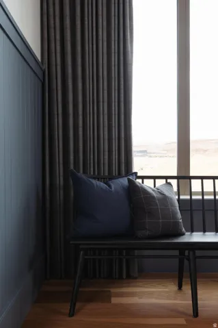 Vertical paneling with a rich blue finish, complemented by full-length dark drapery and wood-finish flooring