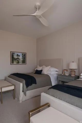 Neutral-toned room featuring a contemporary ceiling fan, wall paneling, and carpeted flooring