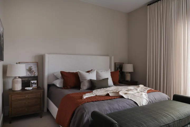 Spacious room featuring a neutral wall color, full-height window drapery, and textured headboard