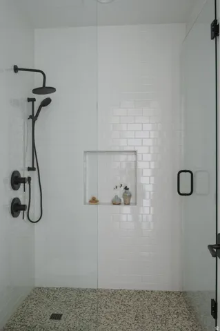 Walk-in shower featuring white subway tile, a recessed niche, black fixtures, and a glass enclosure with black framing