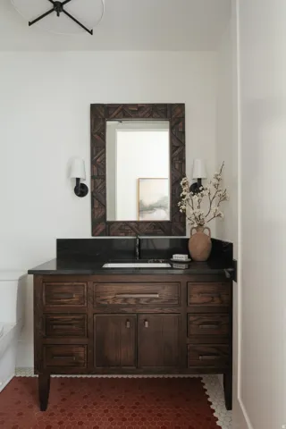 Dark wood vanity with multiple storage drawers and a cabinet, featuring a dark countertop and integrated sink