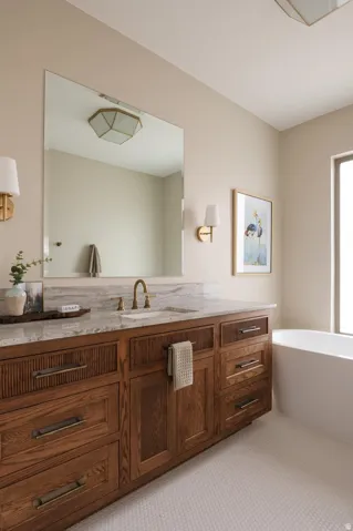 Bathroom vanity featuring a light-toned countertop, integrated sink, and an antique brass finish faucet