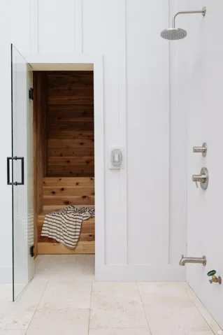 Sauna room with wooden bench seating and a clear glass door
