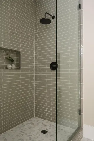 Glass-enclosed shower featuring a matte black rainfall showerhead and coordinating fixtures