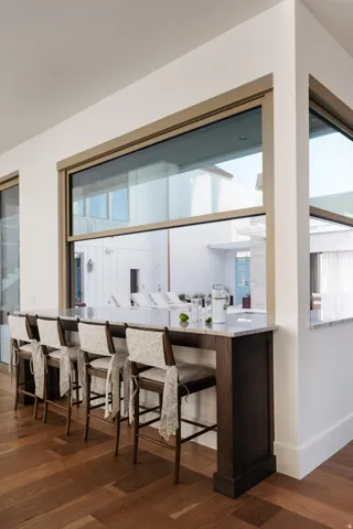 Counter-height bar seating with a light-toned countertop, wood-finish flooring, and expansive windows