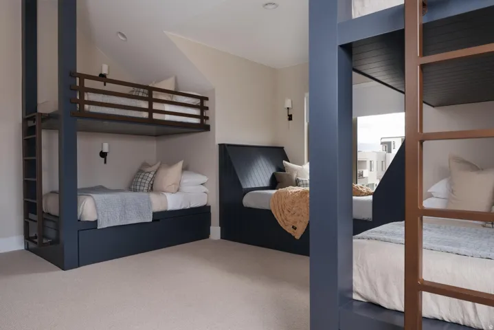 Built-in bunk beds with integrated storage drawers, slatted headboards, and wall-mounted sconces