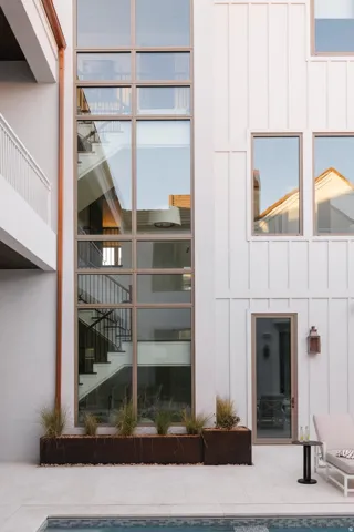 Exterior featuring a towering window wall, white board and batten siding, and a copper downspout