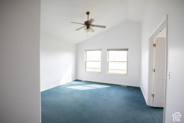 Vaulted ceiling with a ceiling fan, dual windows, and wall-to-wall carpeting
