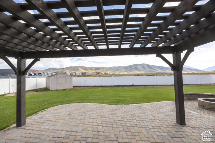 Pergola-covered patio featuring paver stones and an integrated stone fire pit