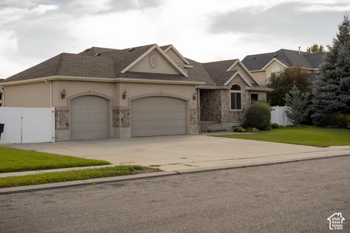 Two-car garage with arched entrances, stucco exterior, stone facade accents, and a front lawn