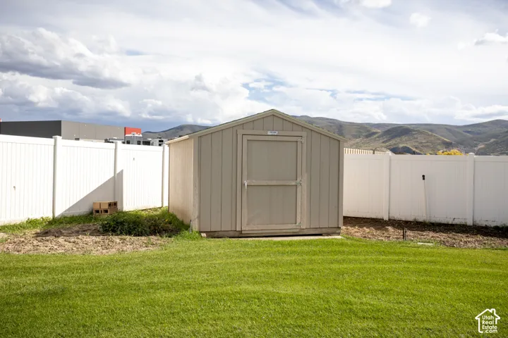 Expansive green lawn with a storage shed and white privacy fencing