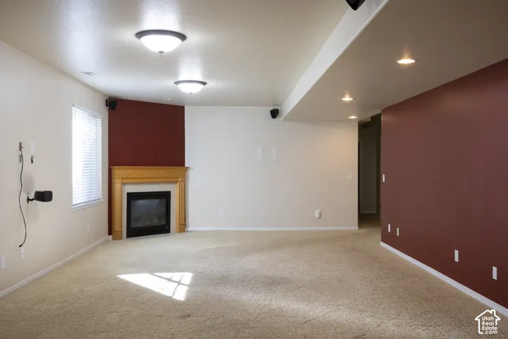 Carpeted floor, built-in fireplace with a wooden mantel, window with blinds, recessed lighting, and flush mount lighting