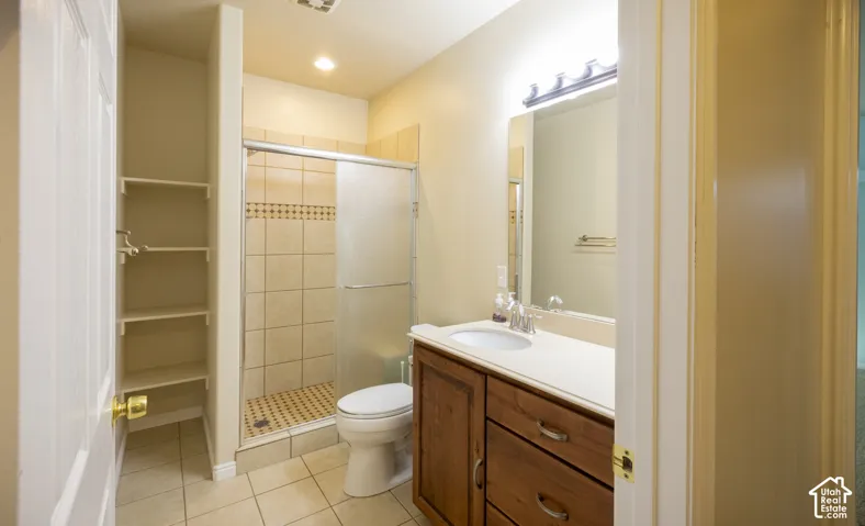 Bathroom featuring a wood-finish vanity with an integrated sink, shower with a sliding glass door, and built-in shelving