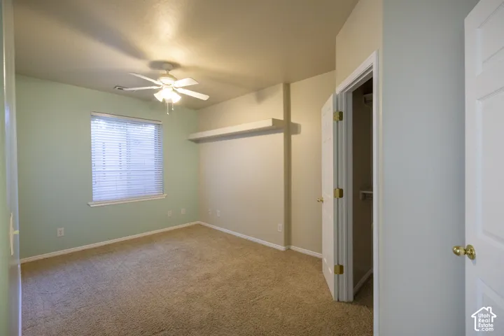 Textured carpeting, ceiling fan with integrated lighting, window with blinds, and built-in closet storage