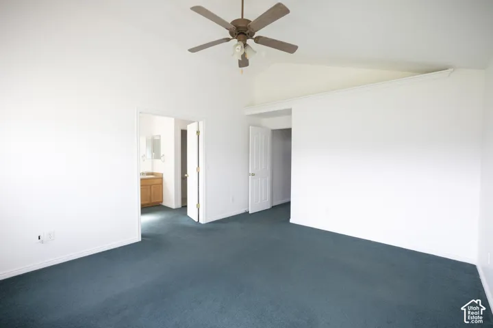 Vaulted ceilings with a ceiling fan, carpet flooring, and a light wood-finish vanity with a mirrored medicine cabinet