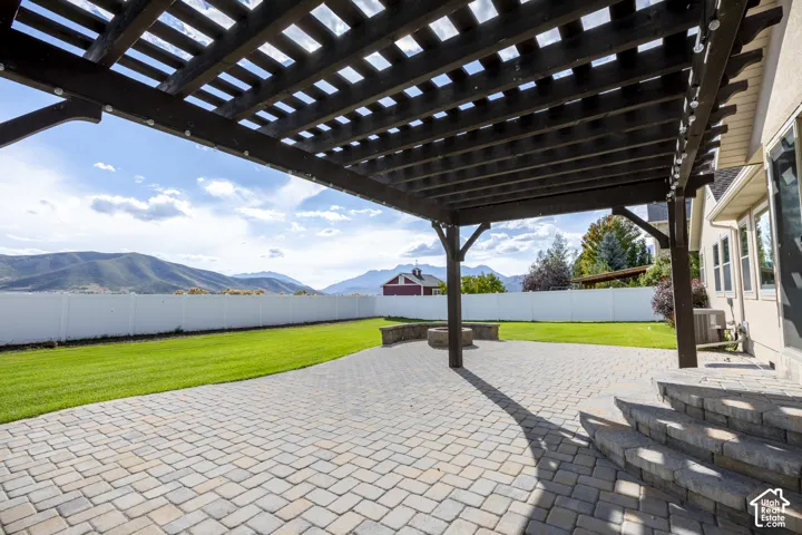 Expansive paver patio with integrated pergola overhead, offering defined outdoor entertaining space