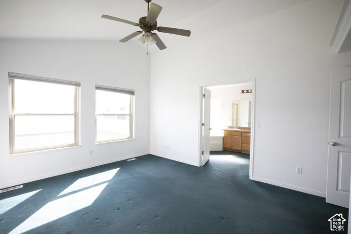 Vaulted ceiling with a ceiling fan, dual windows, and wall-to-wall carpeting
