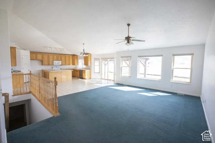 Vaulted ceiling, ceiling fan, multiple large windows, wood-finish cabinetry, tile flooring