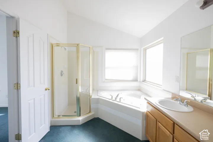 Bathroom featuring a corner shower enclosure, built-in soaking tub, single vanity with a laminate countertop, and a wall-mounted mirror