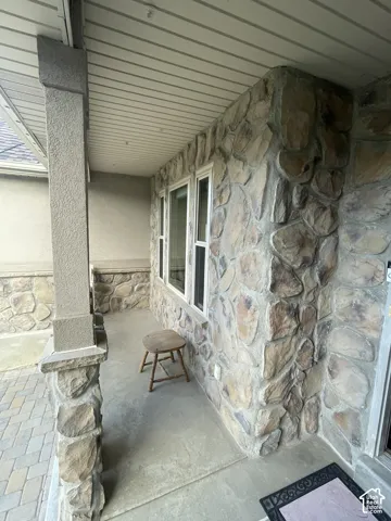 Stone veneer facade with stucco accents, white-framed windows, and a paved entry