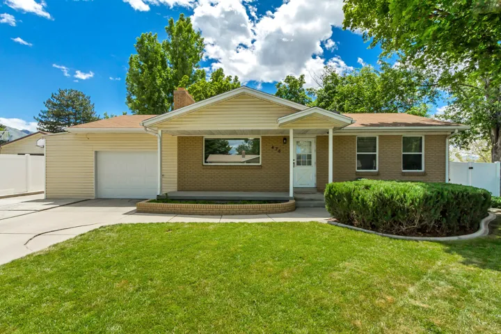 Ranch-style exterior featuring a combination of brick and siding, an attached garage, a paved driveway, and a front porch with an overhang