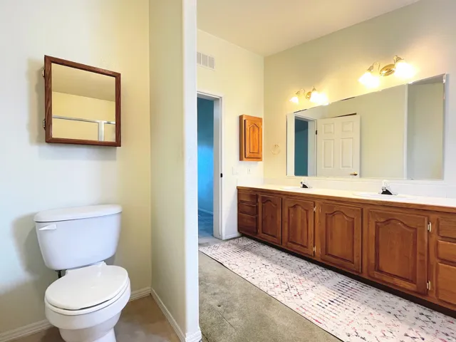 Bathroom featuring a dual vanity with wood cabinetry, integrated sinks, and a large wall-mounted mirror