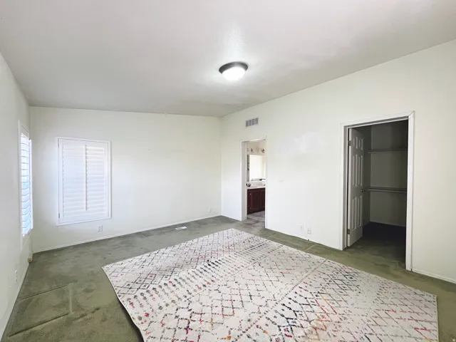 Spacious room featuring neutral painted walls and green carpet flooring