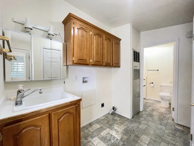 Utility area featuring a built-in sink with cabinetry, wood-finish overhead storage, and patterned tile flooring