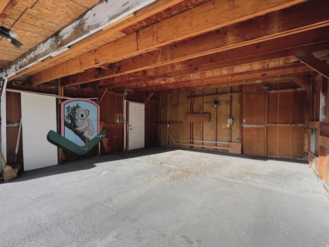 Spacious garage with exposed wood beam ceiling and concrete flooring