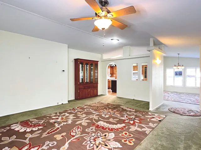 Spacious interior room featuring a ceiling fan with integrated lighting, recessed lighting, carpet flooring, and a partial wall separating spaces
