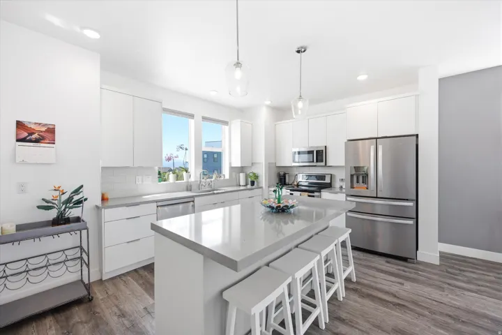 Kitchen featuring stainless steel appliances, white cabinetry, a breakfast bar, and dark wood-type flooring