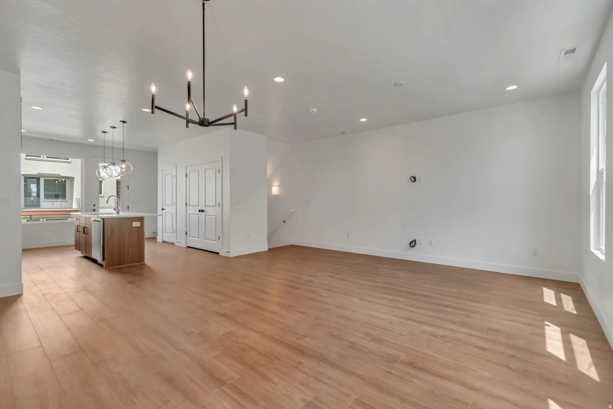 Open-concept area featuring wood-finish flooring, recessed lighting, and a modern chandelier