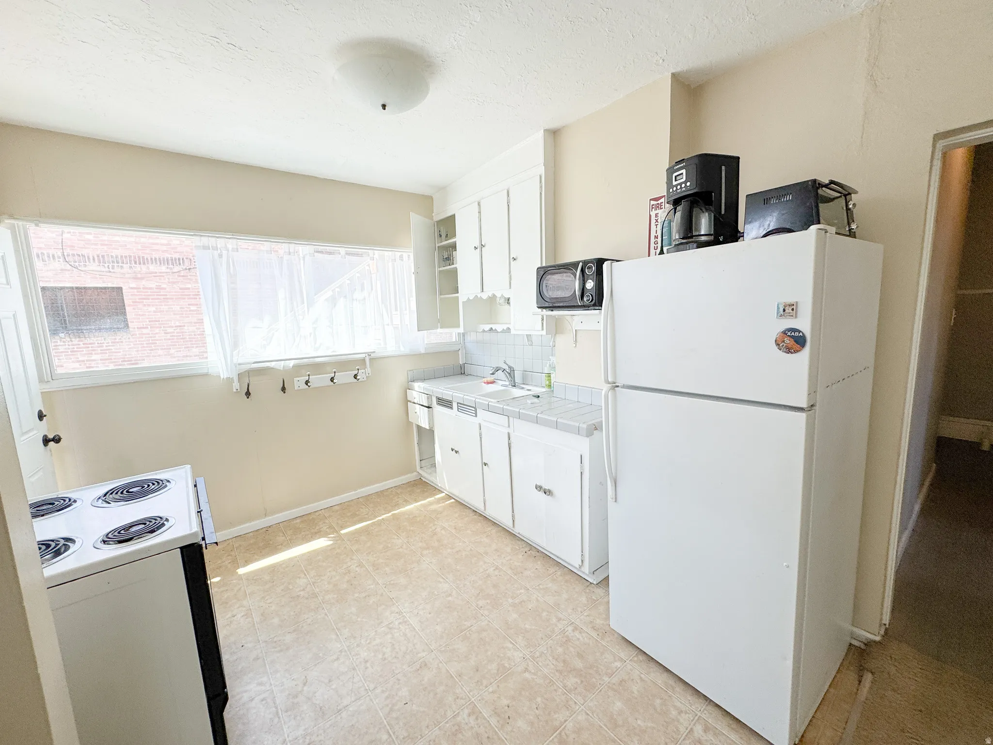 Kitchen featuring a white electric range, white refrigerator, and white cabinetry