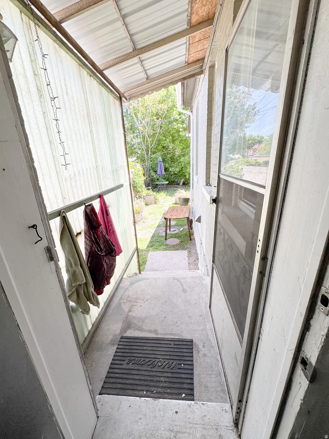 Covered entryway with concrete steps and a corrugated metal roof