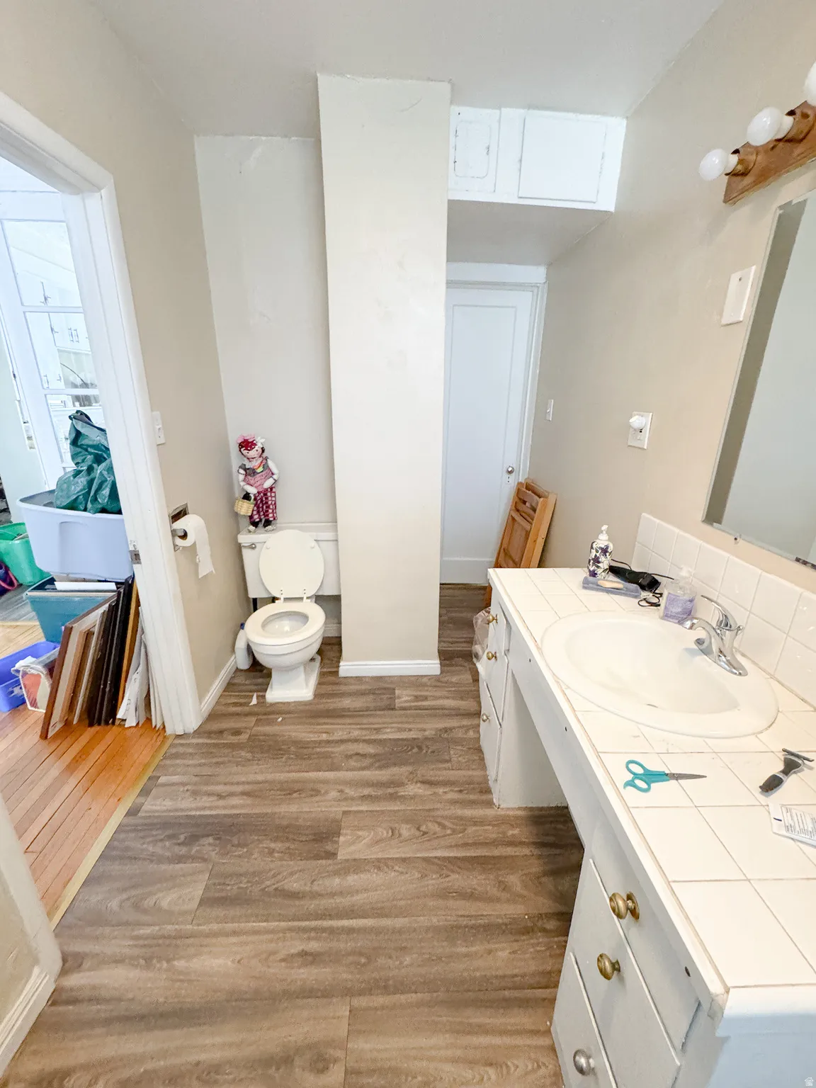 Wood-finish flooring throughout, featuring a white ceramic toilet and a vanity with an integrated sink